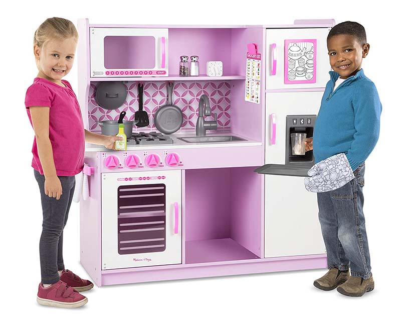Niño y niña jugando en una cocina rosa